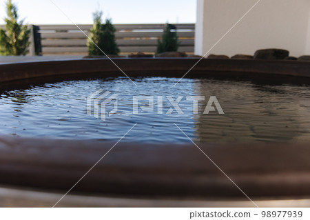 Close-up of modern big hot tub outdoor. Clear water in iron tube. Relaxation on holidays 98977939