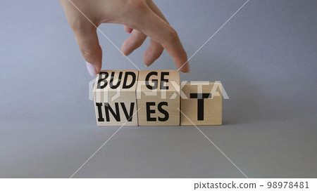 Budget or Invest symbol. Businessman Hand turns cubes and changes word Invest to Budget. Beautiful grey background. Business and Budget and Invest concept. Copy space Budget or Invest symbol. Businessman Hand turns cubes and changes word Invest to Budget. Beautiful grey background. Business and Budget and Invest concept. Copy space 98978481