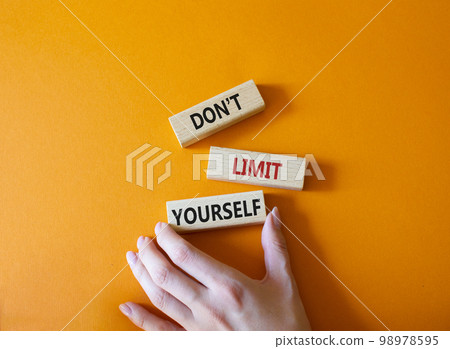 Do not limit yourself symbol. Concept words Do not limit yourself on wooden blocks. Businessman hand. Beautiful orange background. Business and Do not limit yourself concept. Copy space 98978595