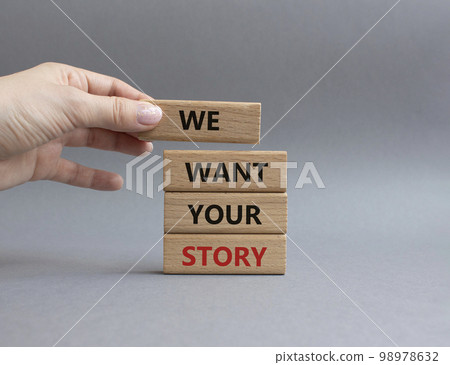 We want your story symbol. Concept words We want your story on wooden blocks. Beautiful grey background. Businessman hand. Business and We want your story concept. Copy space. 98978632