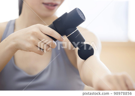 Young woman using myofascial release gun massage gun Young woman using myofascial release gun massage gun 98978856
