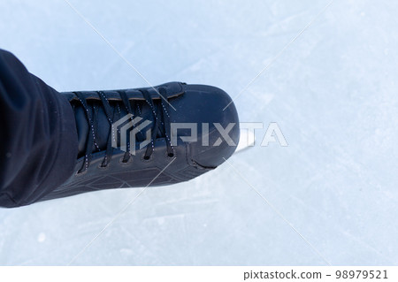 A pair of hockey skates with laces on frozen ice close-up 98979521