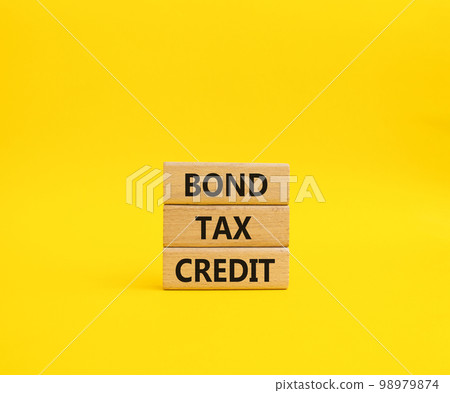 Bond Tax Credit symbol. Concept word Bond Tax Credit on wooden blocks. Beautiful yellow background. Business and Bond Tax Credit concept. Copy space Bond Tax Credit symbol. Concept word Bond Tax Credit on wooden blocks. Beautiful yellow background. Business and Bond Tax Credit concept. Copy space 98979874