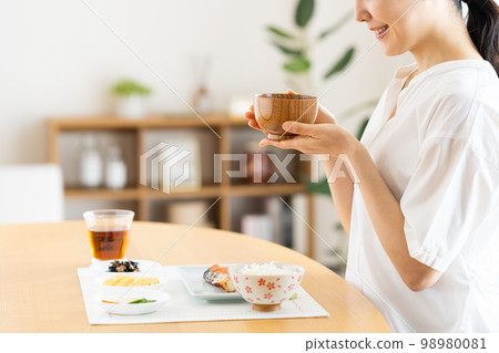 Young woman eating breakfast 98980081