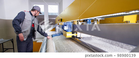 Laundry worker in process of working on automatic machine for carpet washing in dry cleaning 98980139