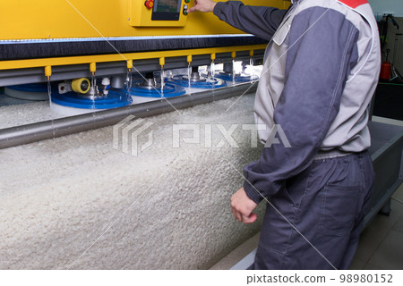 Laundry worker in the process of working on automatic machine for carpet washing in dry cleaning 98980152