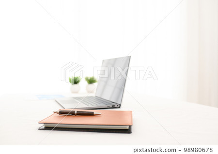 A scene with a laptop, a system notebook, a foliage plant and a pen (pen pinto) on a white table 98980678