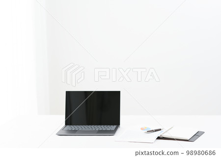 A scene with a laptop, a system notebook, a pen (pen pinto) and materials on a white table 98980686