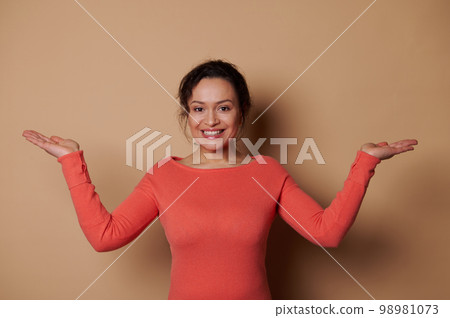 Beautiful woman smiling, holding imaginary copy space for ad on her hands palms up, isolated over beige color background Beautiful woman smiling, holding imaginary copy space for ad on her hands palms up, isolated over beige color background 98981073