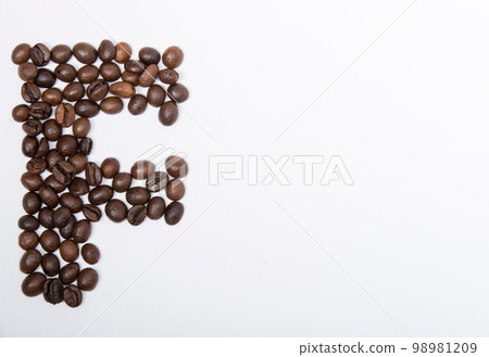 F is a capital letter of the English alphabet made up of natural roasted coffee beans that lie on a white background. Plenty of space to put text or pictures, top view and studio photography. 98981209