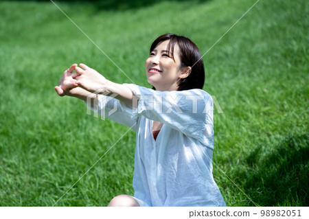 Young woman refreshing on fresh green grass 98982051