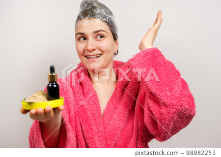 A woman keeps natural cosmetics for hair care - a bottle of oils and ubtan, a scrub of herbs 98982251
