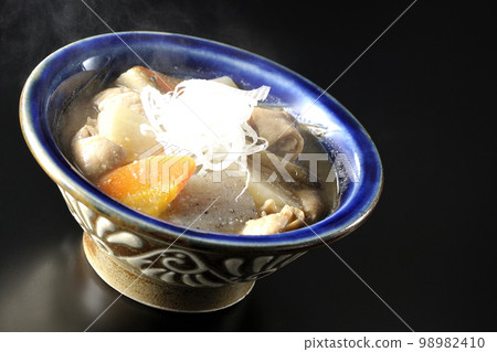 Pork offal stew with carrots, konjac, burdock, and daikon radish on a black background Pork offal stew with carrots, konjac, burdock, and daikon radish on a black background 98982410