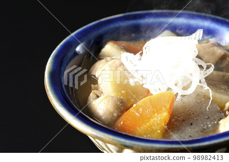Pork offal stew with carrots, konjac, burdock, and daikon radish on a black background Pork offal stew with carrots, konjac, burdock, and daikon radish on a black background 98982413