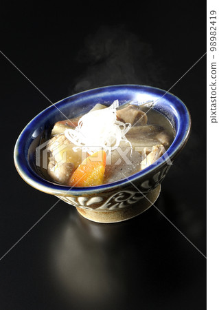 Pork offal stew with carrots, konjac, burdock, and daikon radish on a black background Pork offal stew with carrots, konjac, burdock, and daikon radish on a black background 98982419