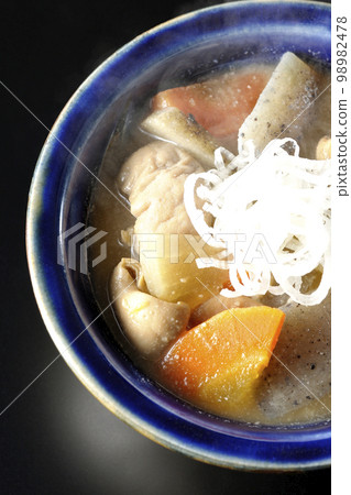 A bird's-eye view of a hot pork offal stew with carrots, konjac, burdock, and radish on a black background A bird's-eye view of a hot pork offal stew with carrots, konjac, burdock, and radish on a black background 98982478