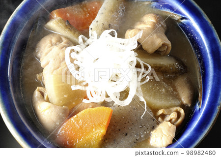 A bird's-eye view of a hot pork offal stew with carrots, konjac, burdock, and radish on a black background 98982480