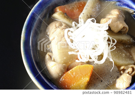 A bird's-eye view of a hot pork offal stew with carrots, konjac, burdock, and radish on a black background 98982481