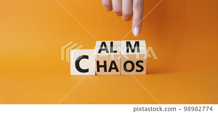 Calm vs chaos symbol. Businessman hand points at turned wooden cubes with words Chaos and Calm. Beautiful orange background. Business and Calm vs chaos concept. Copy space. 98982774