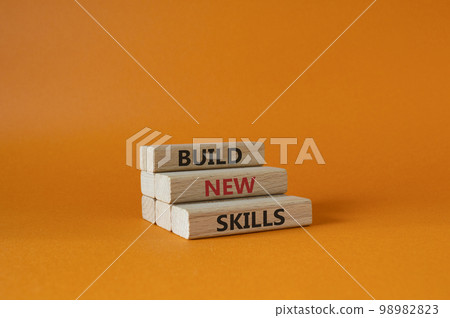 Build New skills symbol. Concept word Build New skills on wooden blocks. Beautiful orange background. Business and Build New skills concept. Copy space Build New skills symbol. Concept word Build New skills on wooden blocks. Beautiful orange background. Business and Build New skills concept. Copy space 98982823