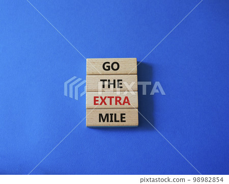 Go the extra mile symbol. Wooden blocks with words Go the extra mile. Beautiful blue background. Business and Go the extra mile concept. Copy space. 98982854