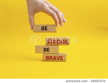 Be strong be brave symbol. Concept words Be strong be brave on wooden blocks. Beautiful yellow background. Businessman hand. Business concept. Copy space. 98982876