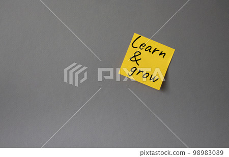Learn and grow symbol. Concept words Learn and grow on orange steaky note. Beautiful grey background. Business and Learn and grow concept. Copy space. 98983089