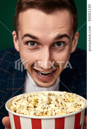Young caucasian man in 3d glasses eating popcorn 98983190
