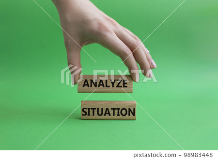 Analyze situation symbol. Wooden blocks with words Analyze situation. Beautiful green background. Businessman hand. Business and Analyze situation concept. Copy space. 98983448