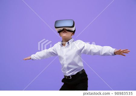 Schoolboy plays video game while using VR headset on purple background. Child in virtual goggles.  98983535