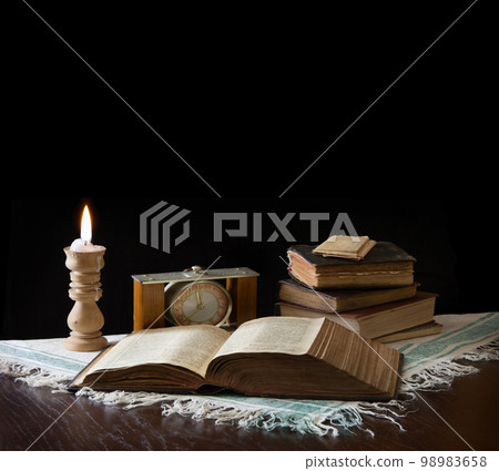 Old bible on the background of a clock and a candle Old bible on the background of a clock and a candle 98983658