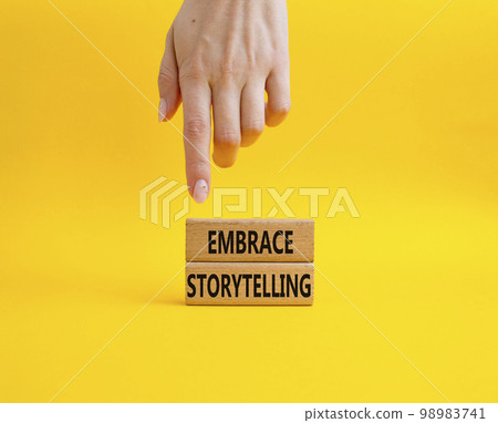 Embrace Storytelling symbol. Concept word Embrace Storytelling on wooden blocks. Beautiful yellow background. Businessman hand. Business and Embrace Storytelling concept. Copy space Embrace Storytelling symbol. Concept word Embrace Storytelling on wooden blocks. Beautiful yellow background. Businessman hand. Business and Embrace Storytelling concept. Copy space 98983741