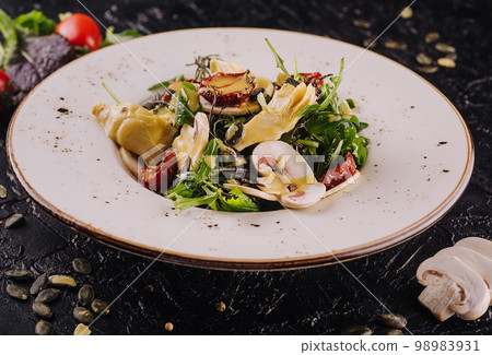 Warm salad with arugula, mushrooms and artichokes Warm salad with arugula, mushrooms and artichokes 98983931