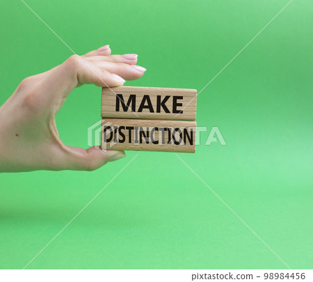 Make distinction symbol. Concept words make distinction on wooden blocks. Beautiful green background. Businessman hand. Business and make distinction concept. Copy space. Make distinction symbol. Concept words make distinction on wooden blocks. Beautiful green background. Businessman hand. Business and make distinction concept. Copy space. 98984456