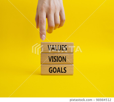 Values Vision Goals symbol. Concept words Values Vision Goals on wooden blocks. Beautiful yellow background. Busimessman hand. Business and Values Vision Goals concept. Copy space. 98984512