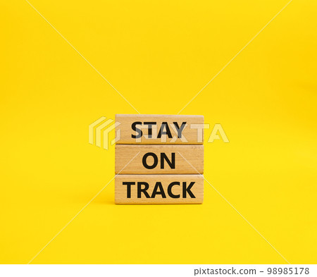 Stay on track symbol. Wooden blocks with words 'Stay on track'. Beautiful yellow background. Business and 'Stay on track' concept. Copy space. Stay on track symbol. Wooden blocks with words 'Stay on track'. Beautiful yellow background. Business and 'Stay on track' concept. Copy space. 98985178
