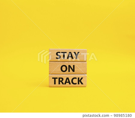 Stay on track symbol. Wooden blocks with words 'Stay on track'. Beautiful yellow background. Business and 'Stay on track' concept. Copy space. Stay on track symbol. Wooden blocks with words 'Stay on track'. Beautiful yellow background. Business and 'Stay on track' concept. Copy space. 98985180