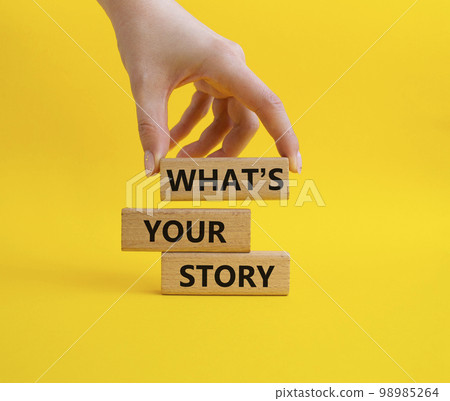 What's your story symbol. Concept words What's your story on wooden blocks. Beautiful yellow background. Businessman hand. Business and What's your story concept. Copy space. 98985264