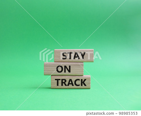 Stay on track symbol. Wooden blocks with words 'Stay on track'. Beautiful green background. Business and 'Stay on track' concept. Copy space. Stay on track symbol. Wooden blocks with words 'Stay on track'. Beautiful green background. Business and 'Stay on track' concept. Copy space. 98985353