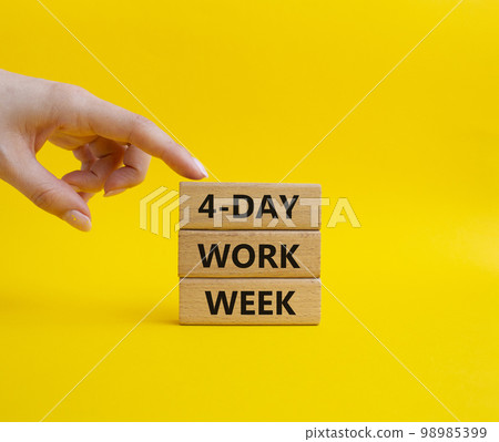 4-day work week symbol. Concept words 4-day work week on wooden blocks. Beautiful yellow background. Businessman hand. Business and 4-day work week concept. Copy space 98985399