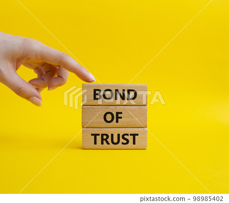 Bond of trust symbol. Wooden blocks with words Bond of trust. Beautiful yellow background. Businessman hand. Business and Bond of trust concept. Copy space. Bond of trust symbol. Wooden blocks with words Bond of trust. Beautiful yellow background. Businessman hand. Business and Bond of trust concept. Copy space. 98985402