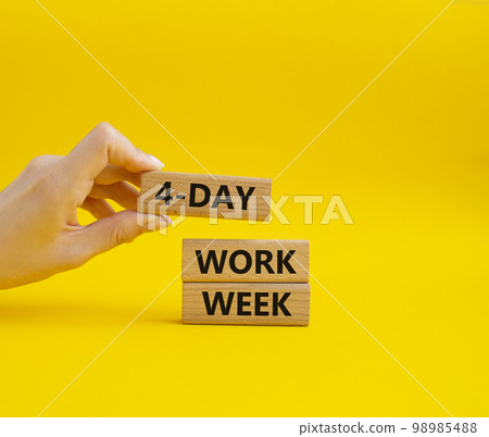4-day work week symbol. Concept words 4-day work week on wooden blocks. Beautiful yellow background. Businessman hand. Business and 4-day work week concept. Copy space 98985488