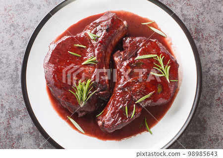 Delicious drunken pork chops fried and then cooked with red wine, herbs and spices close-up on a plate. Horizontal top view 98985643