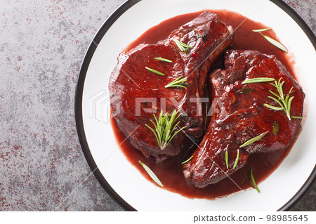 Drunken Pork Chops with red wine sauce and herbs closeup on the plate. Horizontal top view 98985645
