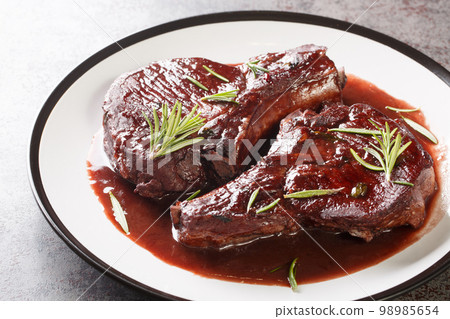 Delicious drunken pork chops fried and then cooked with red wine, herbs and spices close-up on a plate. Horizontal 98985654