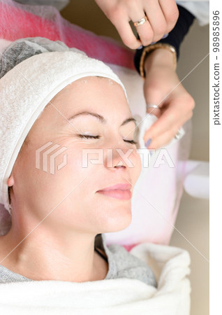 The cosmetologist wipes the remains of the mask with a napkin. 98985896