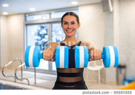 Pretty young fit swimming coach with dumbbells 98985988