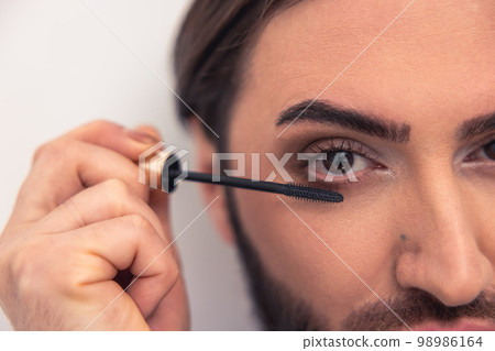 Caucasian male person applying the eye makeup 98986164