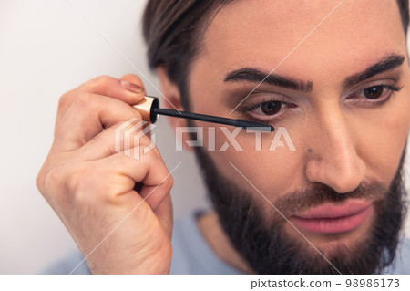 Thoughtful young man applying the eye makeup 98986173