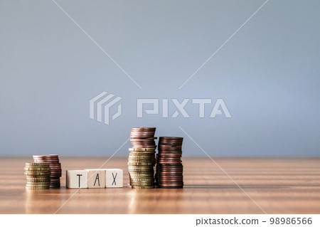Wooden cubes with the word Tax on money climbing staits, pile of coins ,grow increasing tax rates,Tax Concept background closeup Wooden cubes with the word Tax on money climbing staits, pile of coins ,grow increasing tax rates,Tax Concept background closeup 98986566